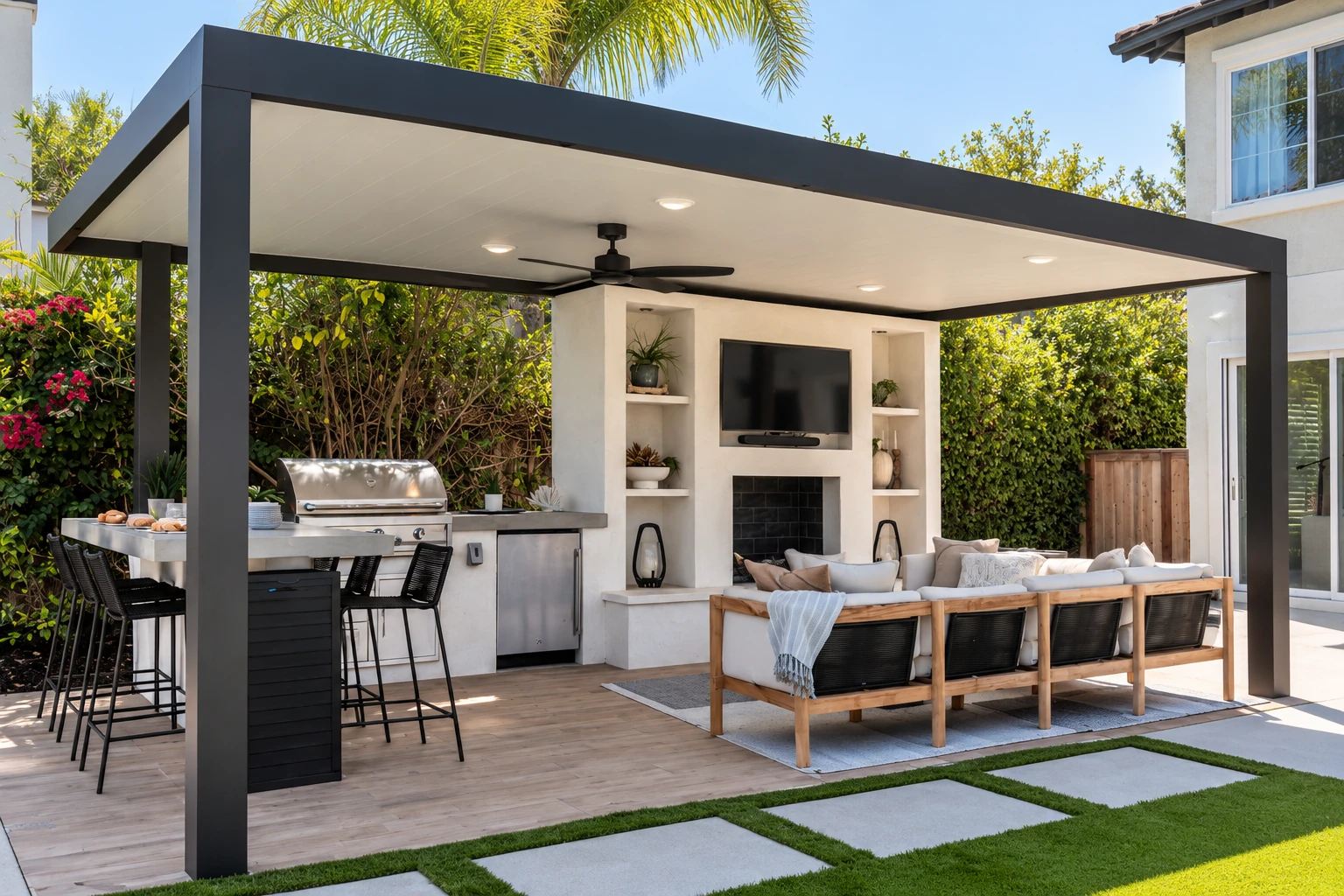 A modern patio cover with a flat roof shades an outdoor kitchen, dining area and lounge seating.